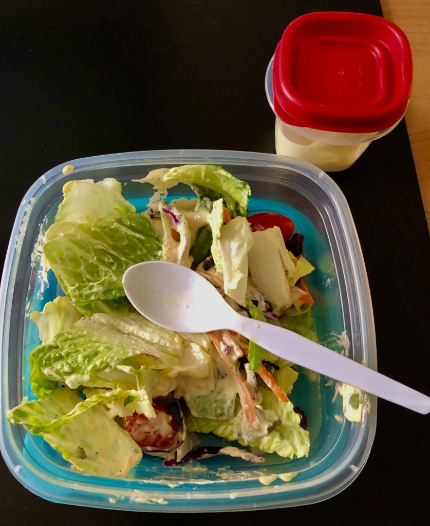 lunch container of salad with a plastic spoon